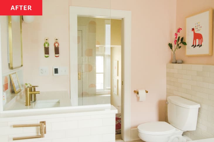 Pink painted kids bathroom with playful art hung on wall after renovation.