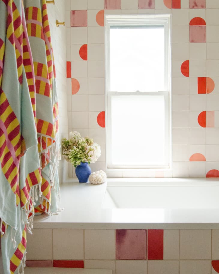 Kids bathroom with red, cream, and pink tile and large tub, and aqua towels