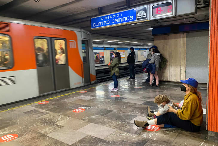 parent and child sitting on floor of Mexico City subway, watching a train approach or leave