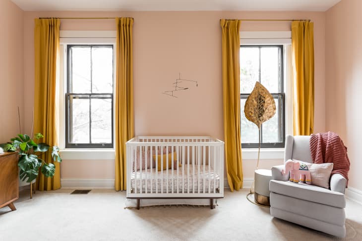 nursery with peach walls and mustard curtains