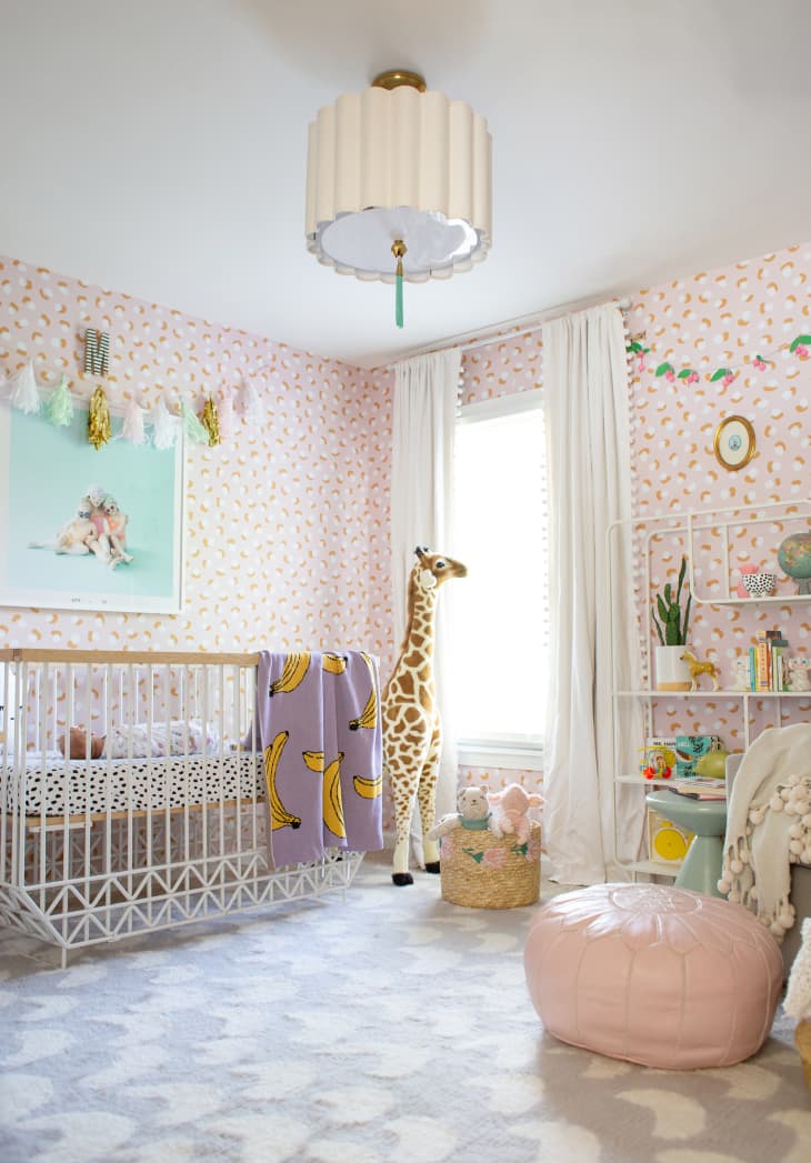 Nursery with pink patterned wallpaper and lots of pastels