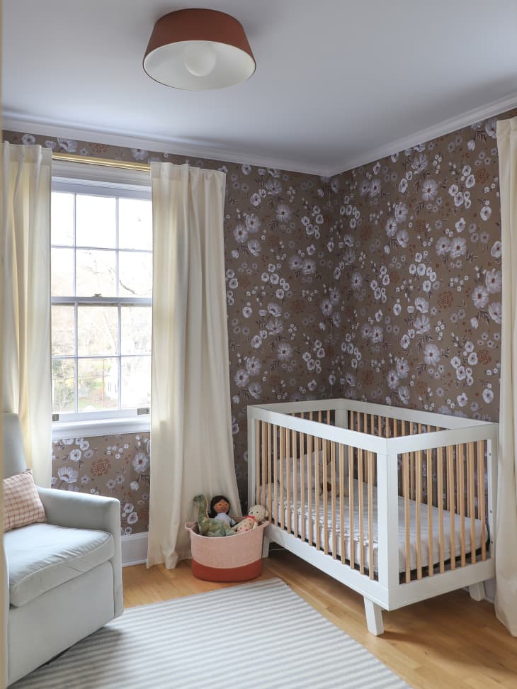 nursery with brown floral wallpaper and white crib