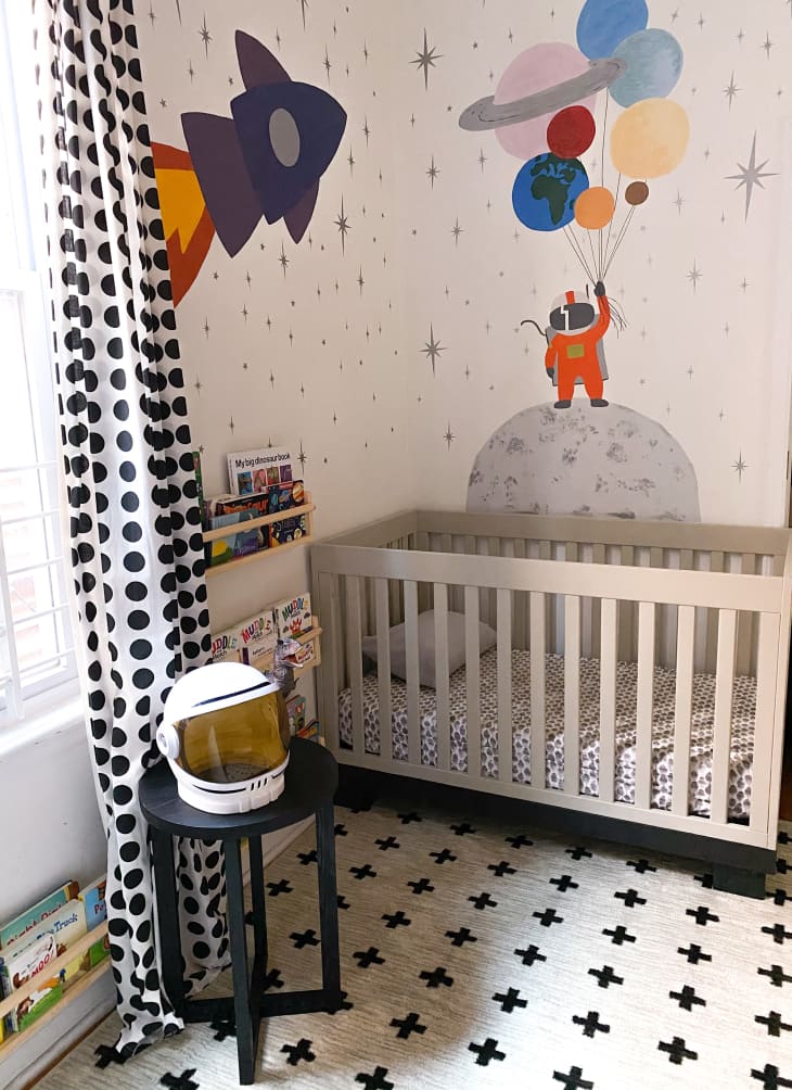 nursery with space travel wallpaper, black and white rug, and other black and white accents