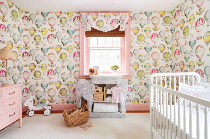 hot air balloon wallpaper in pastels, beige carpet, white crib, elephant shaped changing table