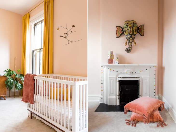 pink walls, gold curtains, white crib, white fireplace with art piece elephant head above it, pink throw pillows