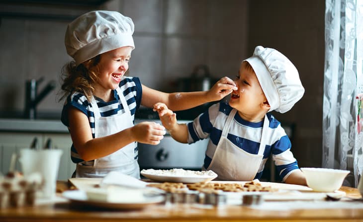 two kids playfully cooking together in the kitchen