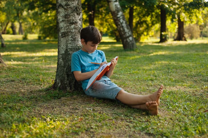 child journaling under a tree