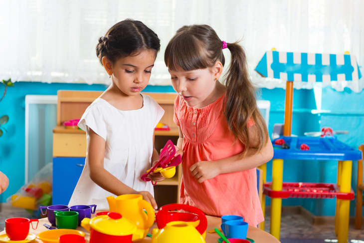 two kids playing together over colorful toys
