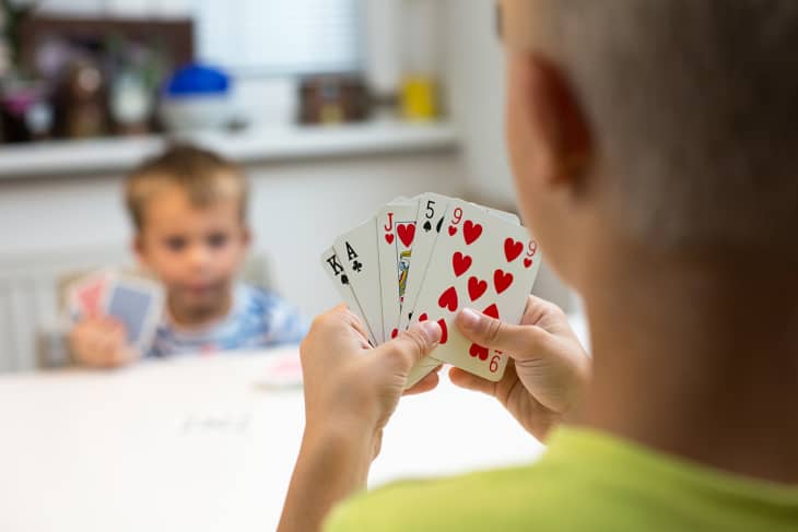boy and parent or brother playing cards at a table in a home.