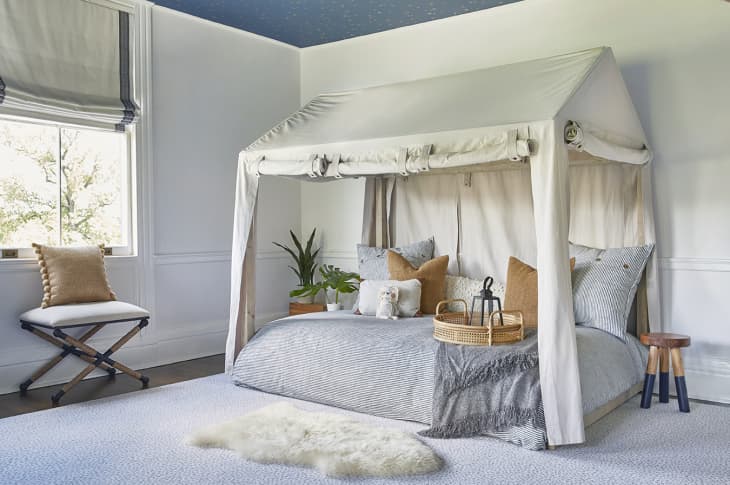 safari themed bedroom with tented bed and pillows against white walls