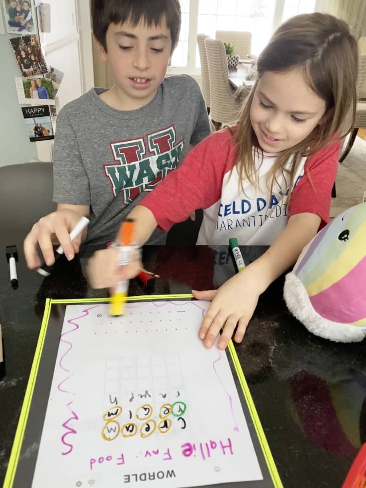 a boy and a girl sitting in front of a homemade Wordle game