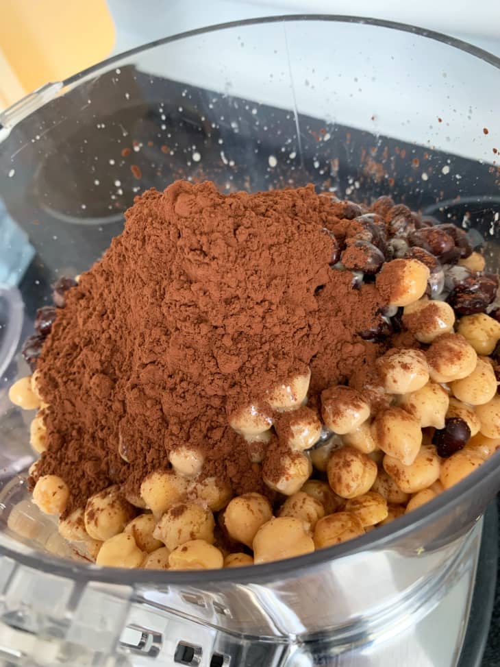 Chocolate hummus in the making in a food processor: chickpeas with a heap of cocoa powder on top.
