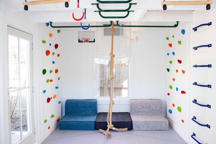 Garage that's been turned into big playroom with all kinds of sports equipment, climbing walls, sofa, climbing rope