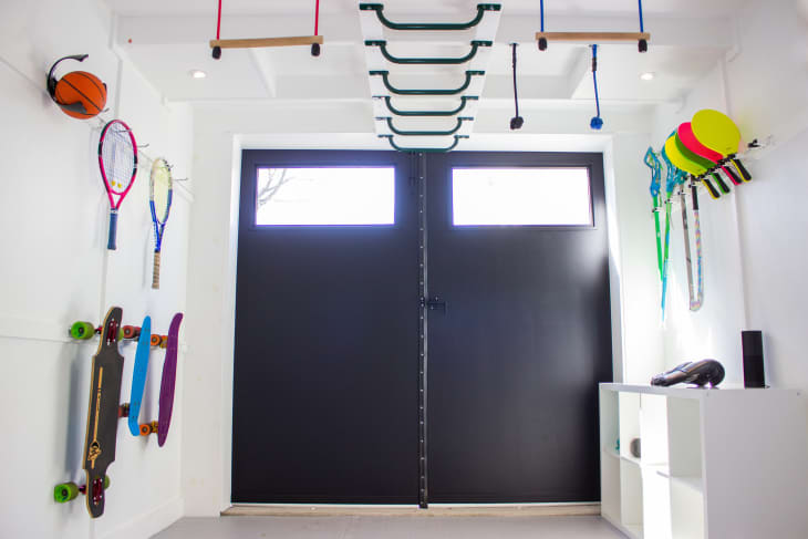 Garage that's been turned into big playroom with all kinds of sports equipment, climbing walls, sofa
