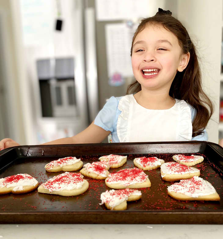 Little girl baking heart-shaped cookies