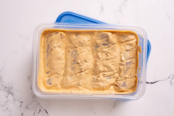 Chicken marinating in a plastic container
