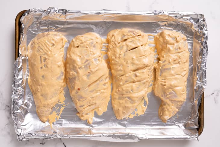 Marinated chicken on tin foil on a sheet pan