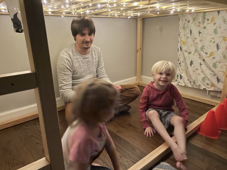 two kids and grownup underneath sparkly lights on Kura iKEA toddler bed