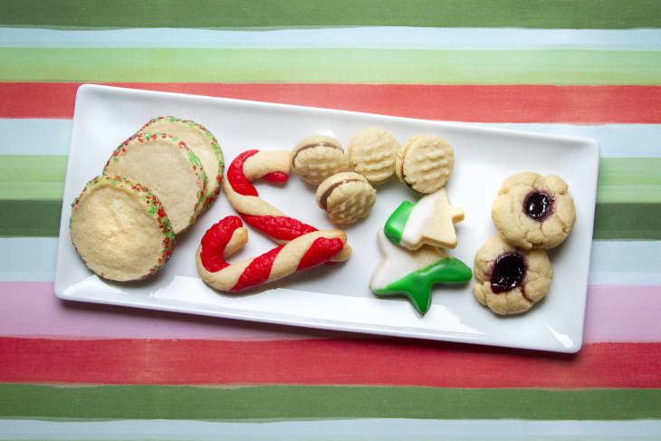 an assortment of holiday cookies on a plate on a striped color background
