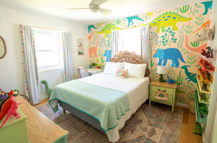 kids' bedroom with dinosaur theme. Dinosaur wallpaper in bright colors, shelves of rainbow toy dinosaurs