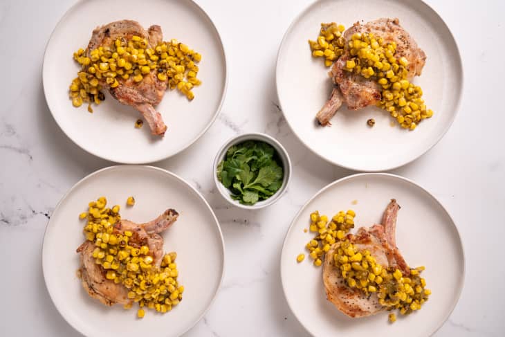 four pork chops with corn salsa plated on white plates