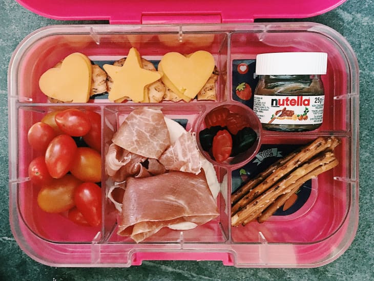 Pink Yumbox lunchbox with a variety of snacks and foods