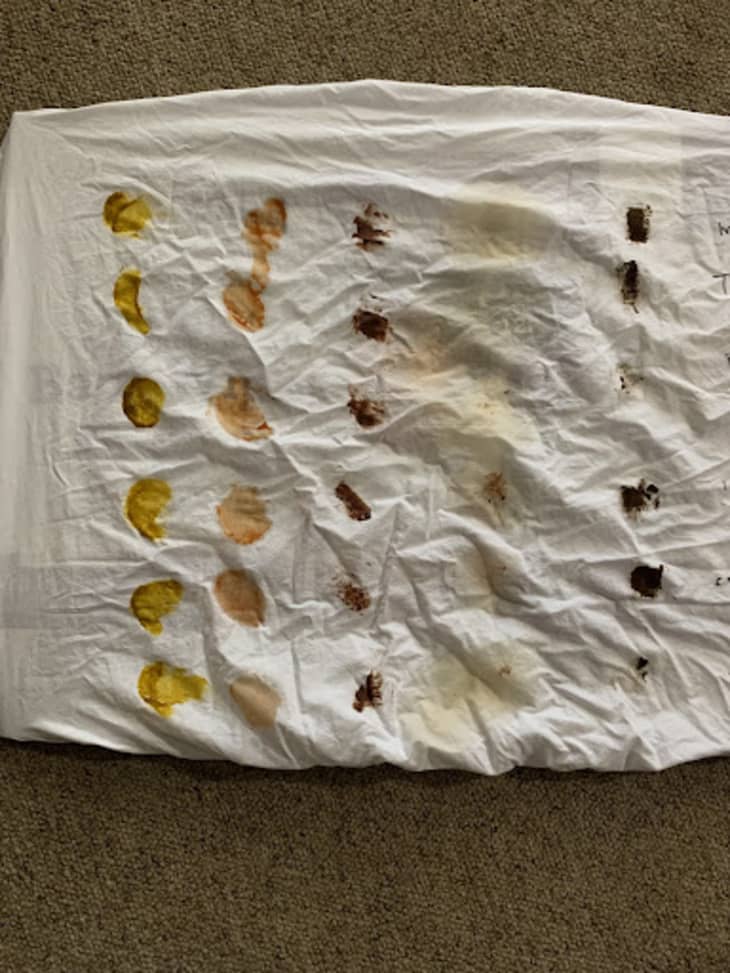 White sheet with stains of chocolate, poop, coffee, mud, and ketchup