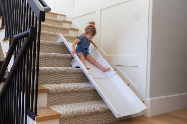 young girl sliding down white stairslide