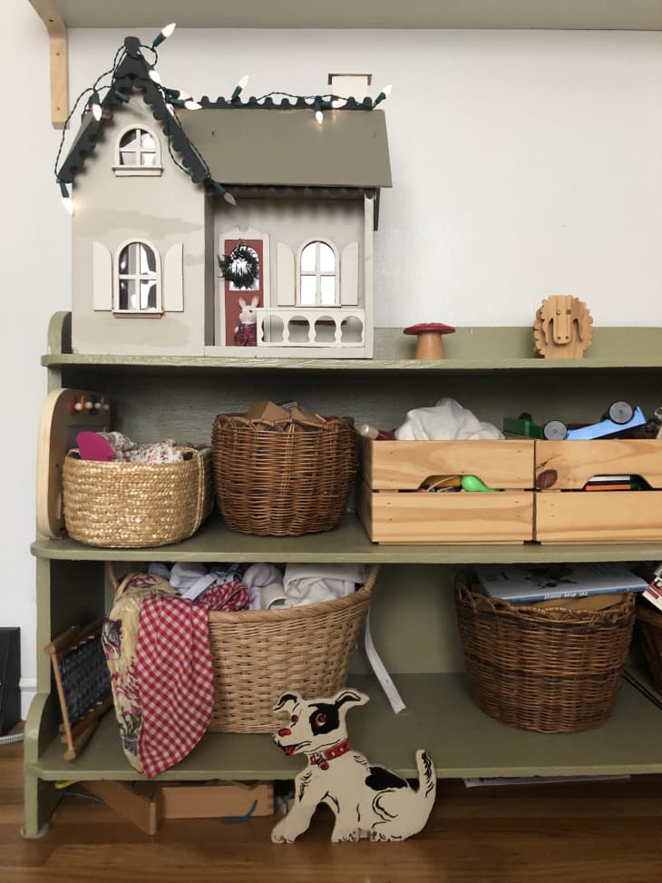 baskets and wooden bins on green shelf with dollhouse
