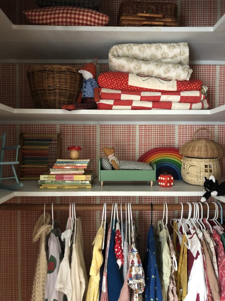 Toys and clothes hanging inside kid's wallpapered closet