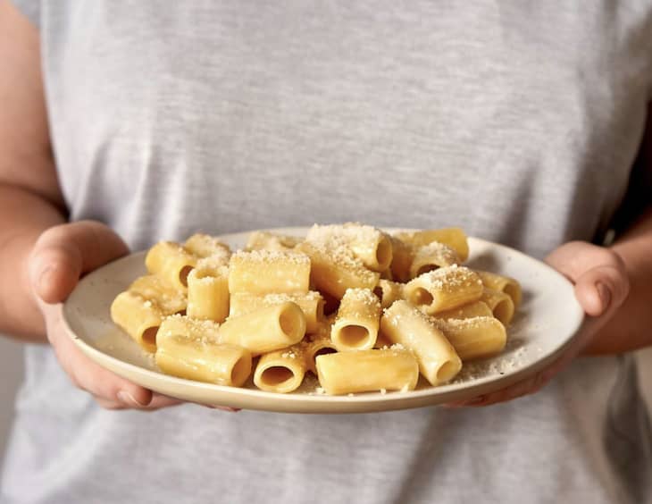 person holding plate of rigatoni pasta