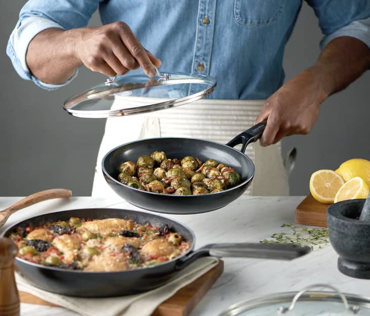 man cooking with two black aluminum nonstick skillets