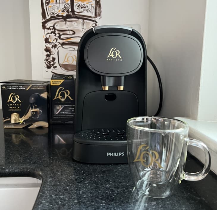 black L'OR coffee machine with glass mug and pods on kitchen counter