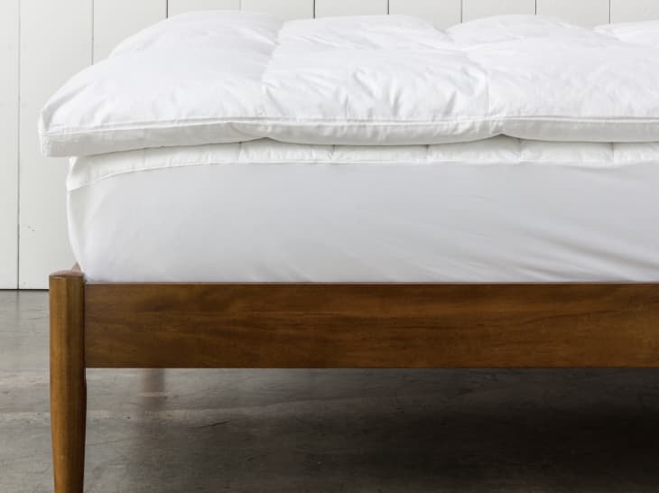 fluffy white mattress topper on wooden bed