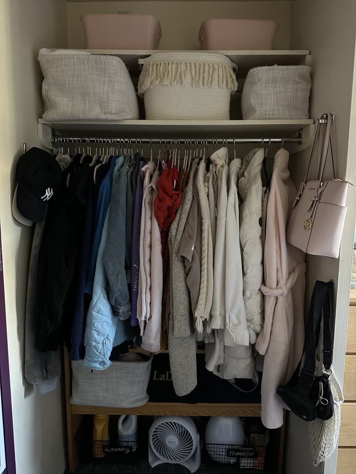 exposed closet, hanging clothes, fabric storage bins, purse, bench storage, small fan, hats