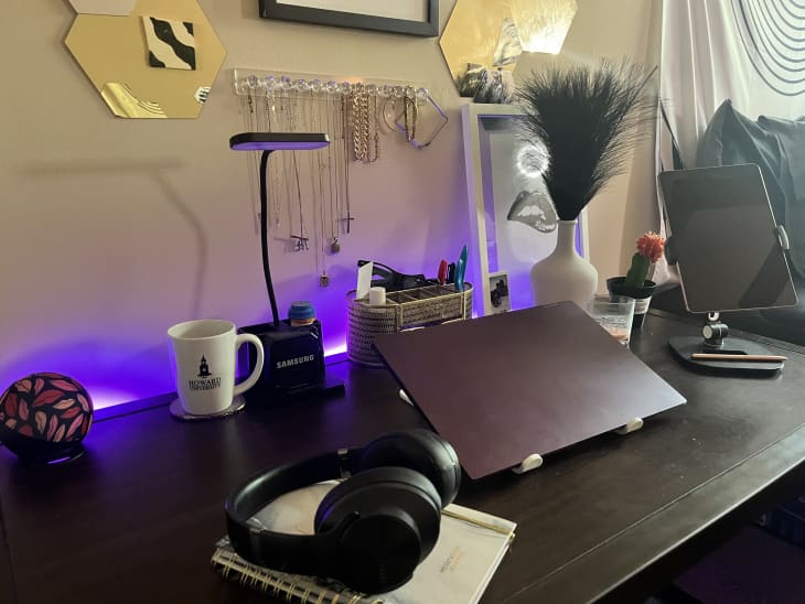 desk, computer, headphones, necklace hanging shelf, desk lamp, ipad, coffee mug, plant, pen holder, purple light