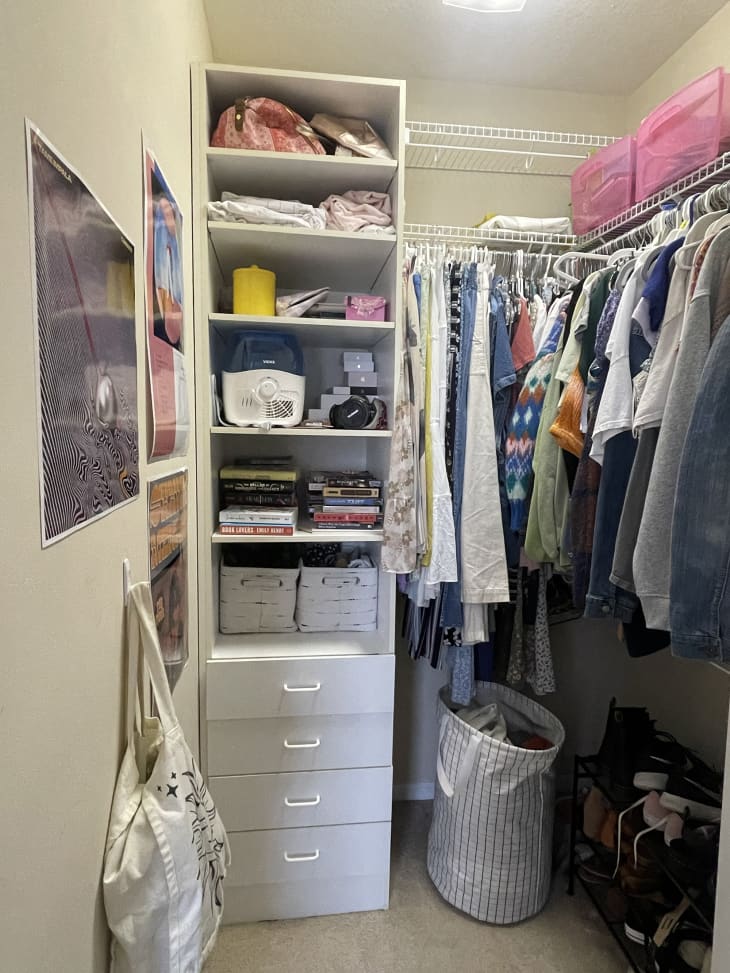 closet in dorm room with tall shelves with books, accessories. Clothes hanging and striped fabric laundry basket and shoe rack on floor. Beige carpet