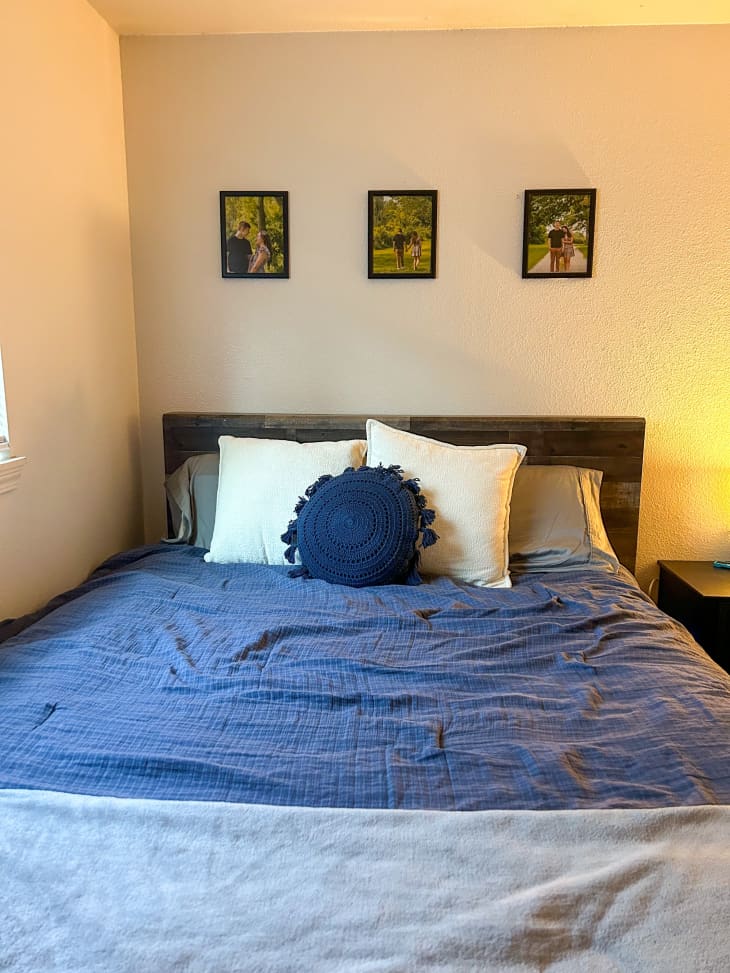 Three framed images above a bed with with blue comforter and white pillows.