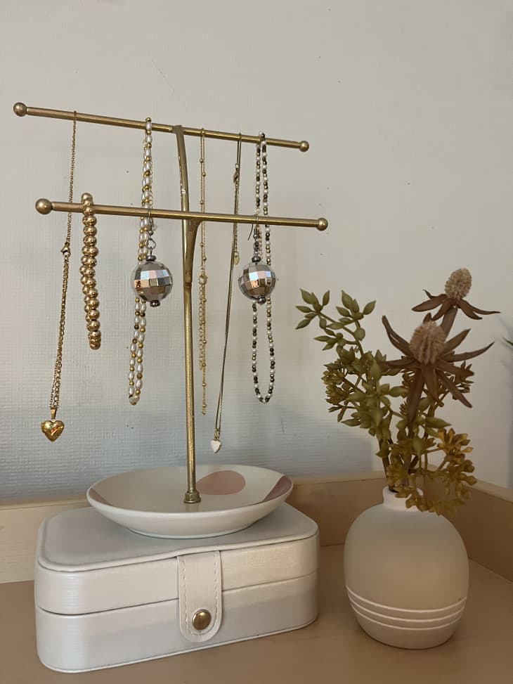 jewelry tree with gold jewelry and small plant, standing on top of small ring plate