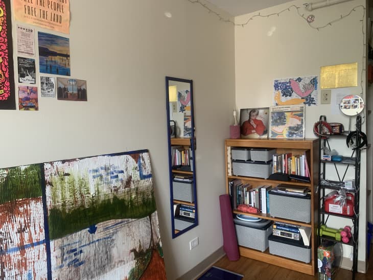 corner of a dorm room with paintings, shelves with organizing bins, and art on the walls