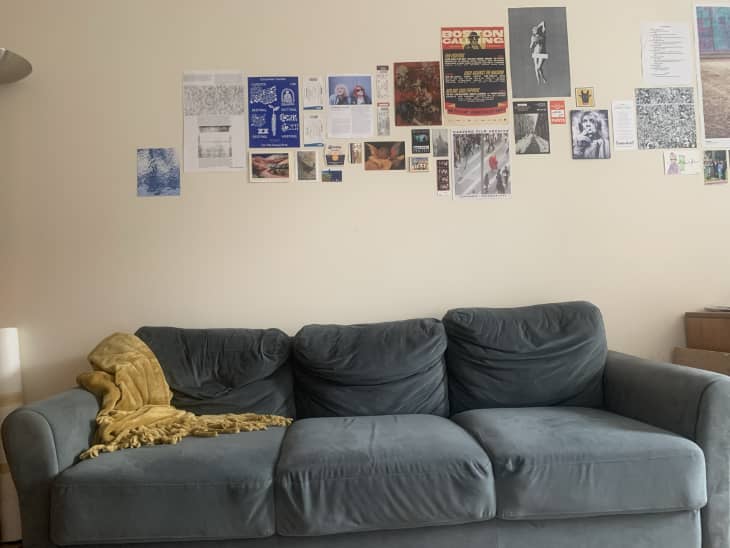 off-white dorm room with gray sofa and lots of art/pictures on the walls