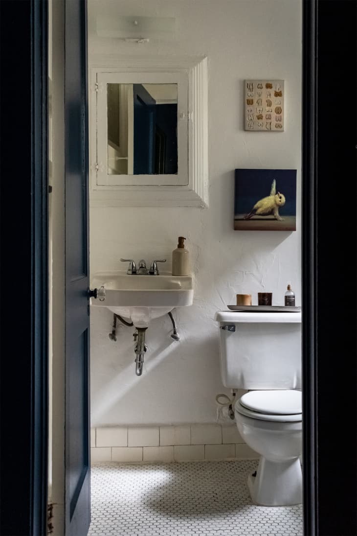 white penny tile on floor white vintage sink, dark blue door and door frame