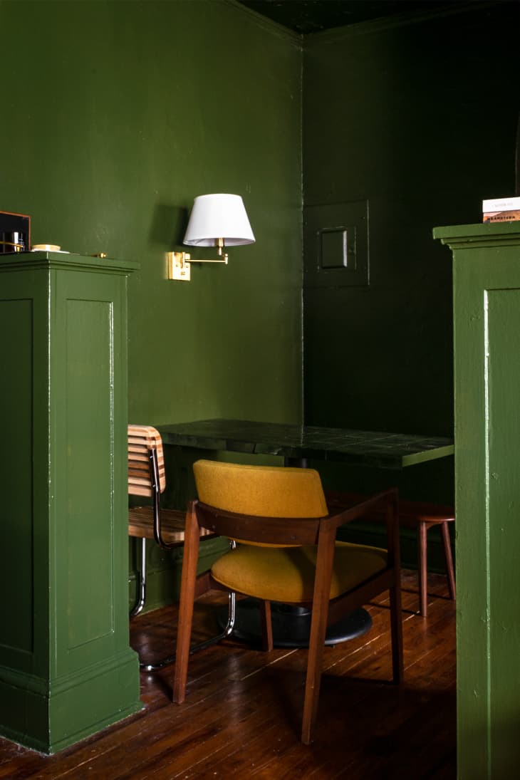 Green walls with small table for two, wall sconce and cane backed mid century modern chairs