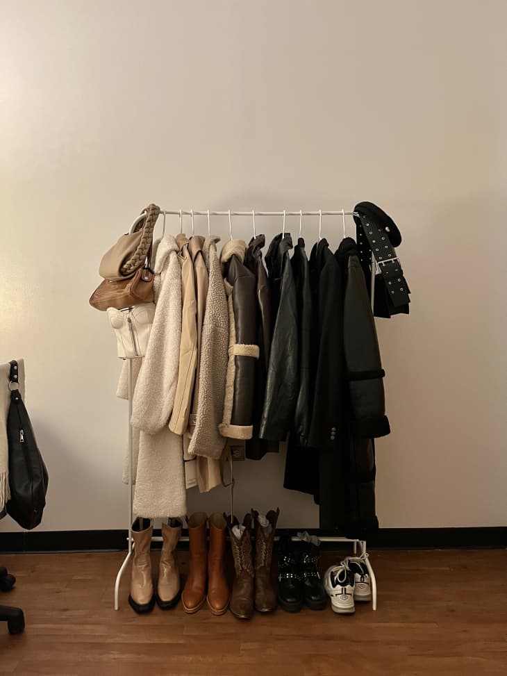 Clothing rack organized by color, light to dark, with boots lined below clothes