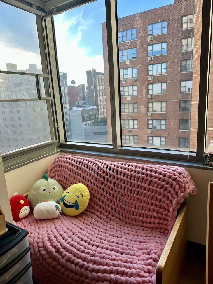 small loveseat with chunky pink throw and view of manhattan out of large windows