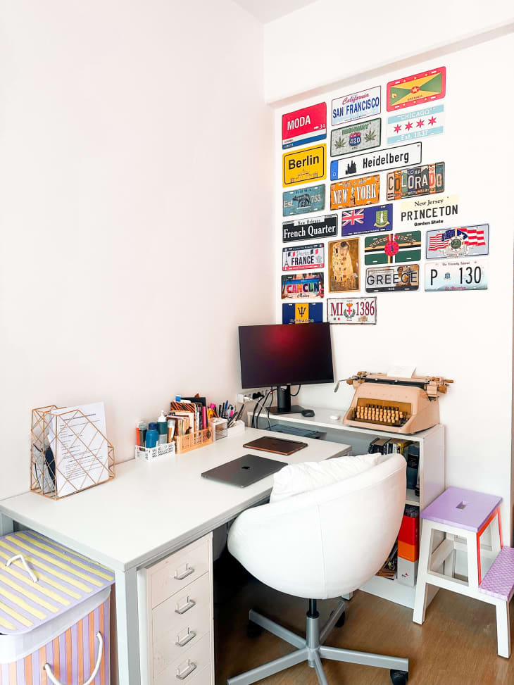 corner desk with white swivel chair and license plates on wall