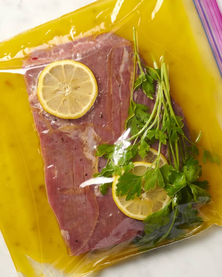 photo of a raw steak in a tenderizing citrus marinade in a gallon zip top bag