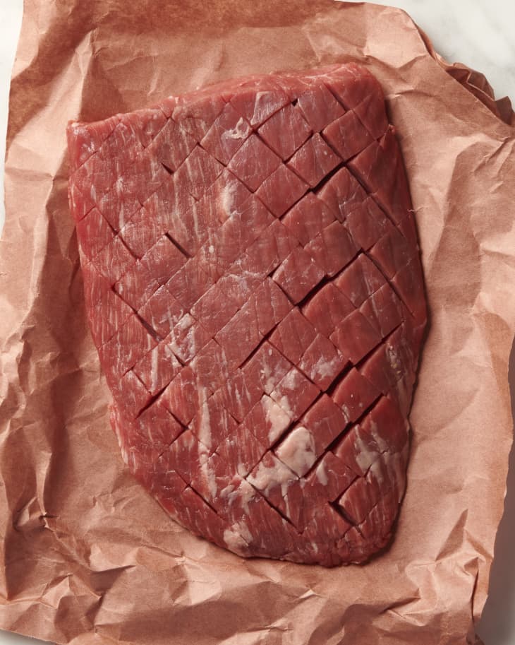 photo of a raw steak on butcher paper that has been tenderized by being scored with a knife