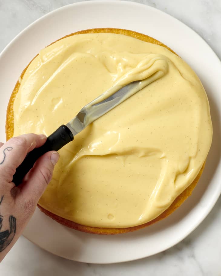 pastry cream being spread onto a cake with an offset spatula