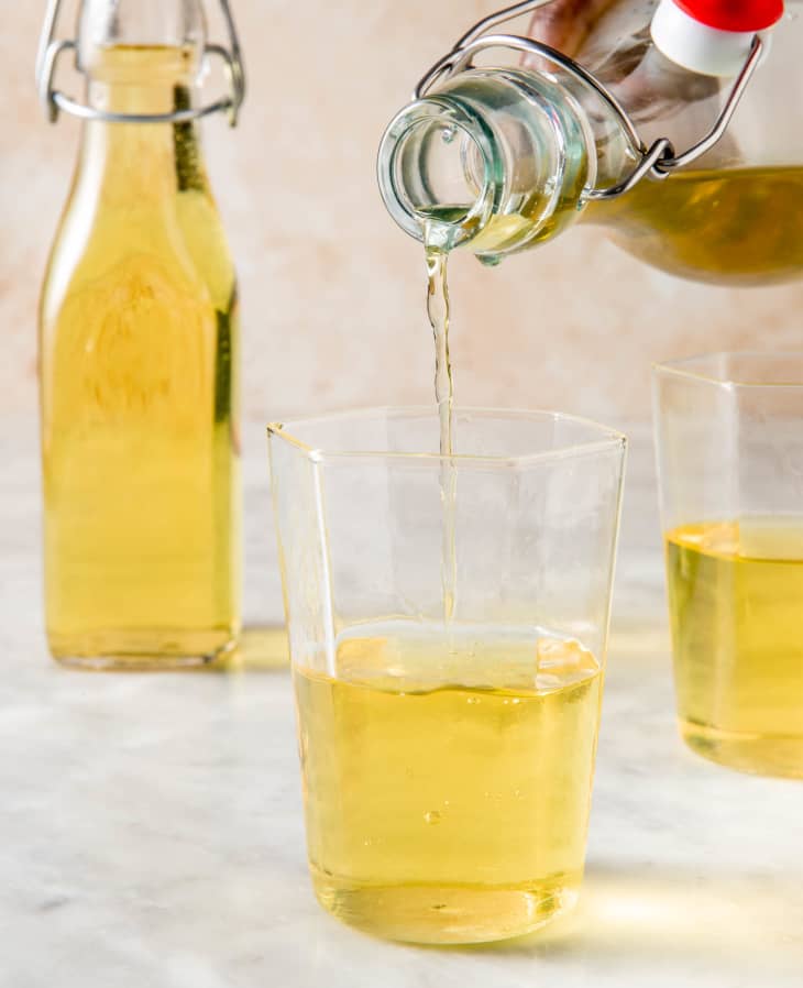 pouring of limoncello into one glass with an extra glass and latch bottle in the background